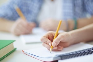 Hand of student with pencil carrying out written task or writing lecture
