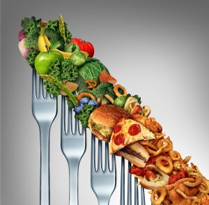 Diet relapse change as a healthy lifestyle slowly goes downward to greasy unhealthy fast food concept as a dieting quality decline symbol of returning to bad eating habits as a group of descending forks with meal items on them.